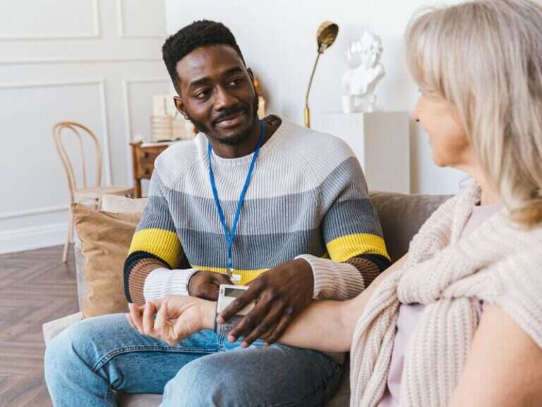 A home care worker sitting with an older woman in her living room