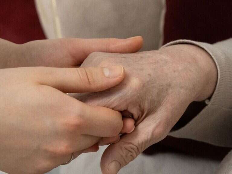 A younger hand resting over an older hand
