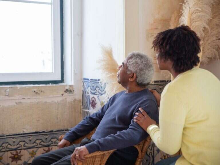 An older man and a woman sitting quietly together by a sunlit window