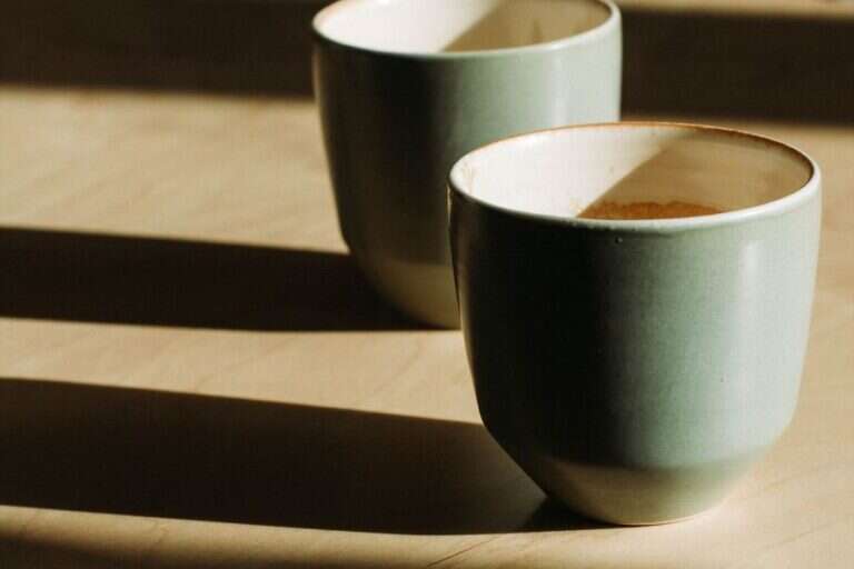 Two cups on a sunlit wooden table